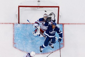 J.T. Brown goes up against Henrik Lundqvist for possession of the puck. Lundqvist, in his first game back from injury, saved 37 of 40 shots. (Image courtesy of TampaBayLightning.com and Scott Audette of Getty Images)