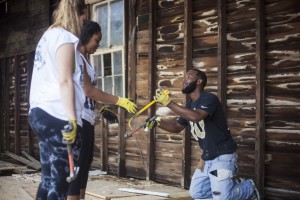 Trey, a supervisor at the construction site USF St. Petersburg students visited in New Orleans, shows Camille Phillips and Dazhane Turman how to use a hammer and crow bar to remove boards.