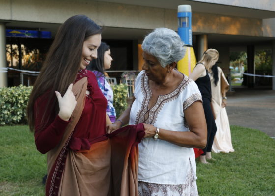Sharing Knowledge: Dana Estrada (left), a junior and business major, getting a lesson before the sari tying competition. Devin Rodriguez | The Crow’s Nest